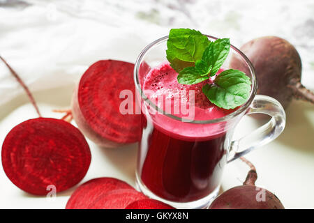 Succo di barbabietola con foglioline di menta e barbabietole disseminate su sfondo bianco Foto Stock