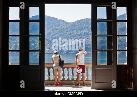 Un giovane si affacciano sul lago di Como dal balcone a Villa Carlotta a Tremezzo, Lombardia, Italia. Foto Stock