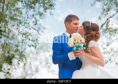 Sposa e lo sposo baciare sullo sfondo di alberi. Foto Stock