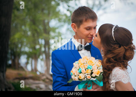 Sposa e lo sposo baciare sullo sfondo di alberi. Foto Stock