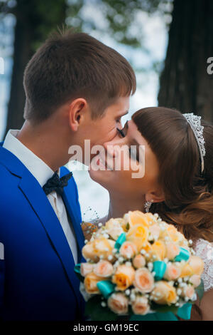 Sposa e lo sposo baciare sullo sfondo di alberi. Foto Stock