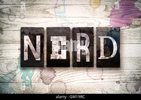 La parola 'nerd' scritto in vintage metallo sporchi tipo di stampa in rilievo su un dipinto di bianco sullo sfondo di legno con inchiostro e macchie di vernice. Foto Stock