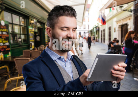 Imprenditore hipster con la compressa. Giorno d'estate in città. Foto Stock