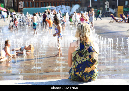 Bambini che giocano in acqua fontane in Piazza Granaio, in una calda giornata estiva, a Kings Cross, a nord di Londra, England, Regno Unito Foto Stock