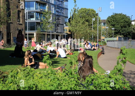 Persone rilassante sull'erba su Wharf Road, vicino a Piazza Granaio, in Kings Cross area di rigenerazione, a Londra NC1, Inghilterra Foto Stock