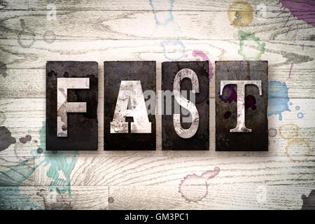 La parola 'Veloce' scritto in vintage metallo sporchi tipo di stampa in rilievo su un dipinto di bianco sullo sfondo di legno con inchiostro e macchie di vernice. Foto Stock