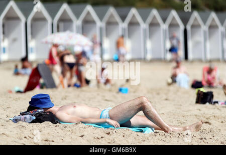 Un uomo sunbathes su Branksome Chine spiaggia di Bournemouth, come un ondata di caldo fa sì che parti del paese di sizzle. Foto Stock