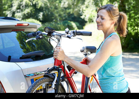 Femmina matura ciclista prendendo in Mountain Bike dalla cremagliera sulla vettura Foto Stock