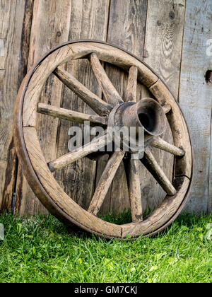 Vecchio Carro di legno ruota in appoggio contro il rustico di recinzione di legno Foto Stock