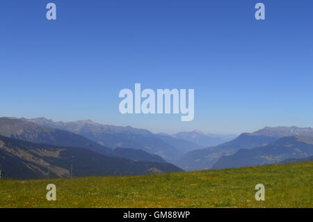 I pendii sopra Méribel ski resort in Francia nel periodo estivo con cielo blu, verdi pascoli e panorama di montagna Foto Stock