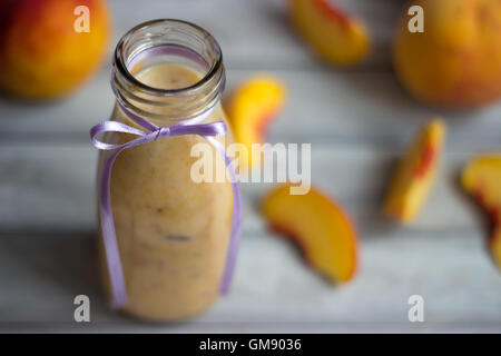 Pesche frullato e su sfondo di legno Foto Stock