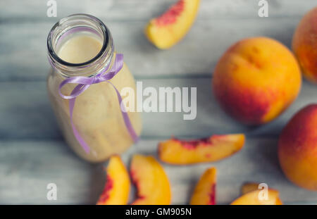 Le pesche e le pesche smoothie su sfondo di legno Foto Stock