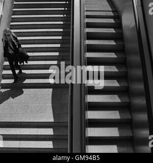 La donna per le scale della metropolitana stazione della metropolitana nel centro di Atene, Grecia. In bianco e nero. Foto Stock