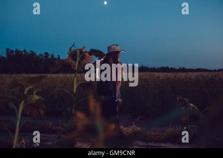 Ha perso nel campo di girasole si siede su una valigia. In attesa di aiuto. Notte. Foto Stock