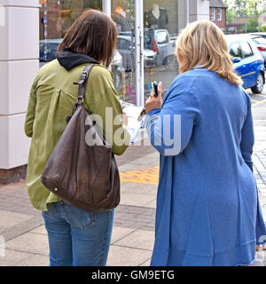 Donna in possesso di appunti (dati inseriti sfocati) intervista e domande donna acquirente in piccolo centro città mercato Street sondaggio donne UK Foto Stock