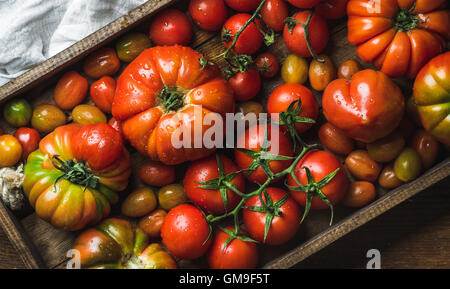 Pomodori colorati di diverse dimensioni e tipi di legno scuro vassoio Foto Stock