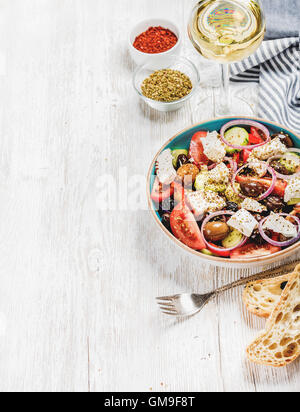 Insalata greca con pane, erbe e bicchiere di vino bianco Foto Stock