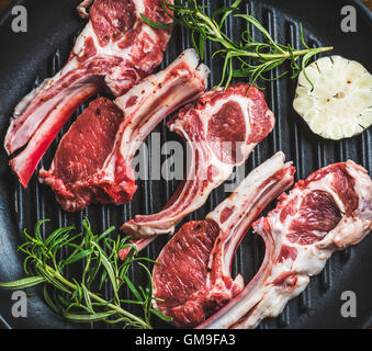 Materie non cotti agnello costolette di carne di pollo con rosmarino e aglio Foto Stock