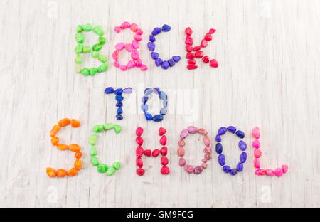 Si torna a scuola scritto con pietre colorate su sfondo di legno Foto Stock