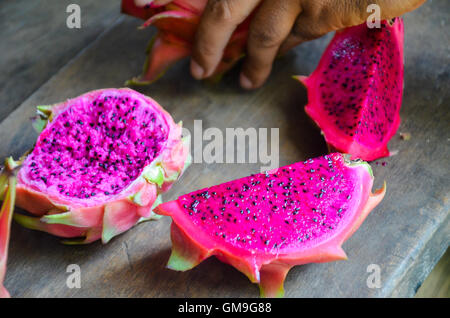 Vivaci e brillanti drago rosso frutta tagliata sul vecchio tavolo in legno, Chi Phat, Cambogia Foto Stock