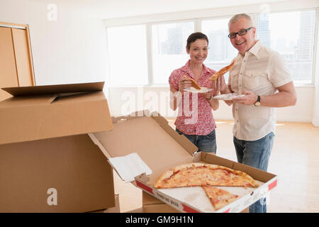 Ritratto di Coppia sorridente mangiare la pizza nel nuovo appartamento Foto Stock