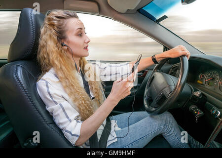 Donna che utilizza il telefono cellulare durante la guida auto Foto Stock