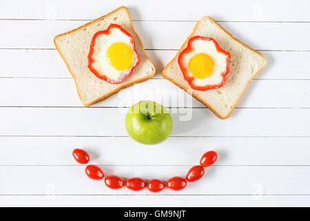 Sorridente faccia alimentare. Il cibo della colazione concetto, sandwich di uovo, apple e pomodori Foto Stock