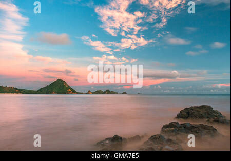 Una lunga esposizione dell'oceano ancora e rocce e con un bellissimo cielo al tramonto. Foto Stock