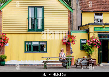 Una donna si siede da solo al di fuori di un Pub di campagna in East Sussex, Regno Unito Foto Stock