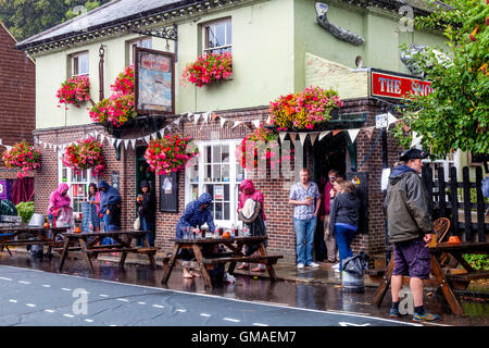 Persone riparo dalla pioggia al di fuori della Snowdrop pub della città mercato di Lewes, East Sussex, Regno Unito Foto Stock