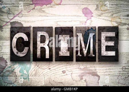 La parola "crimine" scritto in vintage metallo sporchi tipo di stampa in rilievo su un dipinto di bianco sullo sfondo di legno con inchiostro e macchie di vernice. Foto Stock