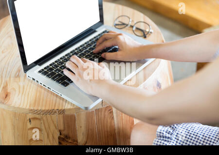 Donna di mano sul laptop computer notebook con degli occhiali sulla scrivania in legno Foto Stock