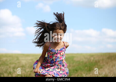 Felice bambina in esecuzione in campo estivo Foto Stock