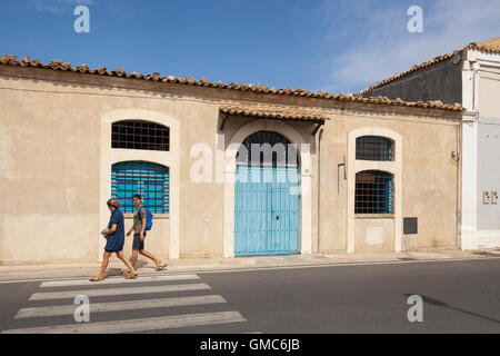 I turisti oltrepassando un vecchio edificio, Marzamemi, Sicilia, Italia Foto Stock