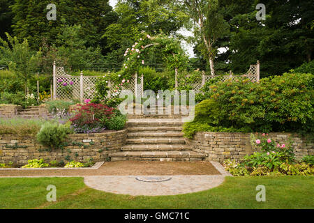 Mosaico, piante, passaggi e le rose intorno a un trellis arch - progettato e paesaggistici, giardino, Burley in Wharfedale, nello Yorkshire, Inghilterra. Foto Stock