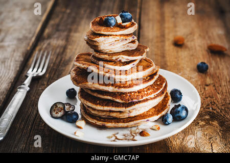 Pila di frittelle, frumento integrale pancake con mirtilli e miele sul tavolo di legno Foto Stock