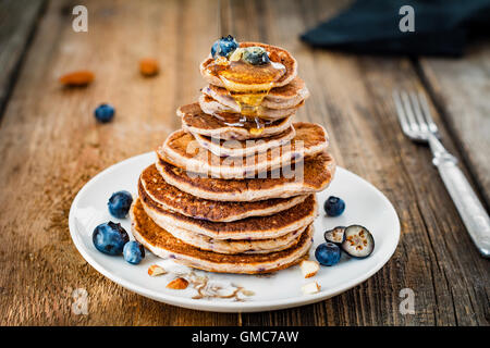 Pila di frittelle, frumento integrale pancake con mirtilli e miele sul tavolo di legno Foto Stock