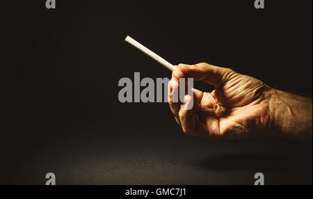 Composizione concettuale sul fumo, studio shot di una mano di un uomo in possesso di un sigaro. Foto Stock