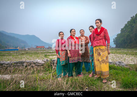 Ritratto di donne, abitanti di Khahare, in quanto si trovano vicino a un muro di gabione sul lato della pianura alluvionale di Harpan Khola a Kaski, Gandaki, Nepal. Foto Stock