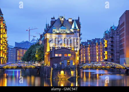 Casa e due spose illuminata di sera nel vecchio quartiere di magazzino (Speicherstadt), Amburgo, Germania Foto Stock