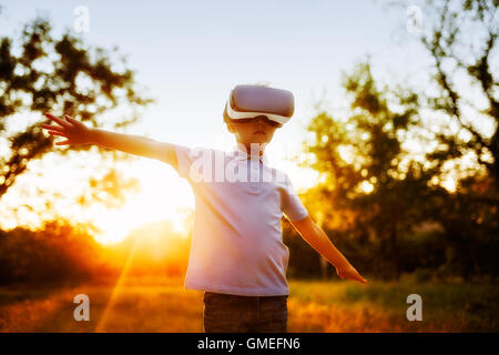 Affascinato little boy utilizzando VR la realtà virtuale gli occhiali di protezione esterna Foto Stock