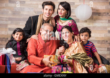 Famiglia indiana celebra diwali festival o compleanno mediante lo scambio di doni, ben 3 generazioni della famiglia indiana e doni e dolciumi, Foto Stock