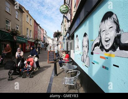 La gente passa un murale su Michael Street che fa parte delle mura di Waterford graffiti e street art festival che si svolgono tra 25 e 28 agosto nella città di Waterford, Irlanda. Foto Stock