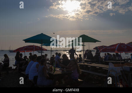 Mersey Isola, Essex, 25 agosto 2016. Persone godere del sole serale presso il West Mersea piatti a base di frutti di mare e il ristorante Oyster, affacciato su yacht e barche da pesca ormeggi. Credito: Paolo Davey/Alamy Live News Foto Stock
