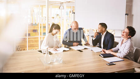 Quattro uomini di affari che ridere durante una pensione professionale sala meeting Foto Stock