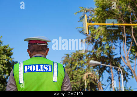 Polizia indonesiana officer in giacca fluorescente sul dovere permanente sulla strada Foto Stock