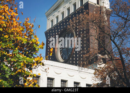 Foglie di autunno di fronte del clock e la torre campanaria della chiesa del Sacro Cuore di nostro Signore di Praga e cielo blu. Foto Stock