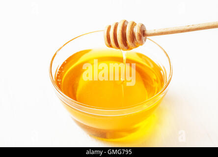 Il bilanciere per il miele e il miele in una ciotola su sfondo bianco Foto Stock