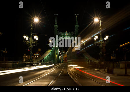 Vista notturna di tram e automobili attraversando Ponte della Libertà a Budapest, Ungheria Foto Stock