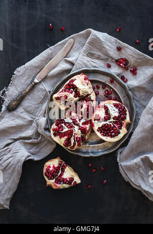 Rosso maturo pelato melograno rustico sulla piastra di metallo e beige asciugamano da cucina Foto Stock